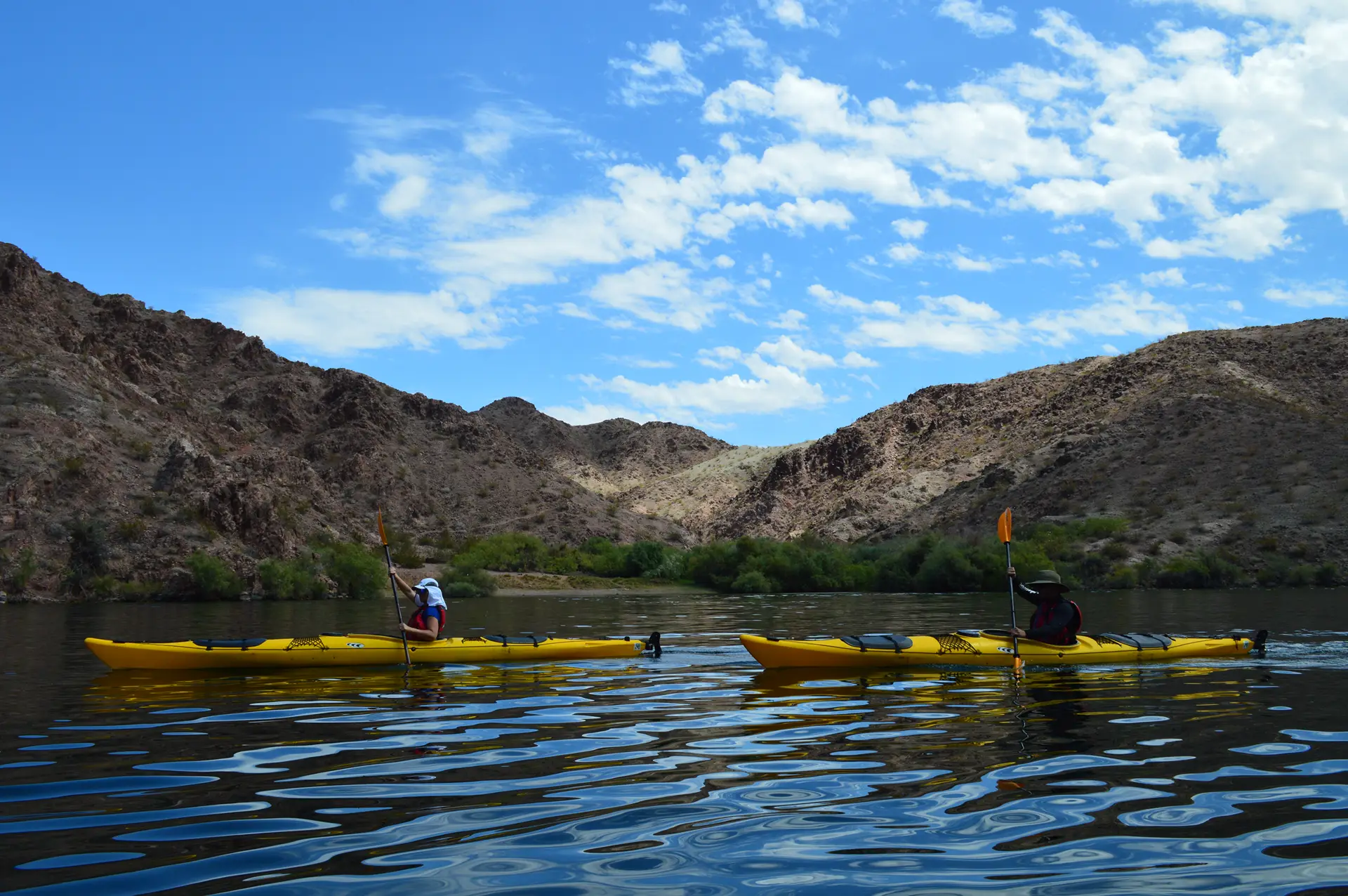 Two yellow kayaks paddling side by side on the Colorado River